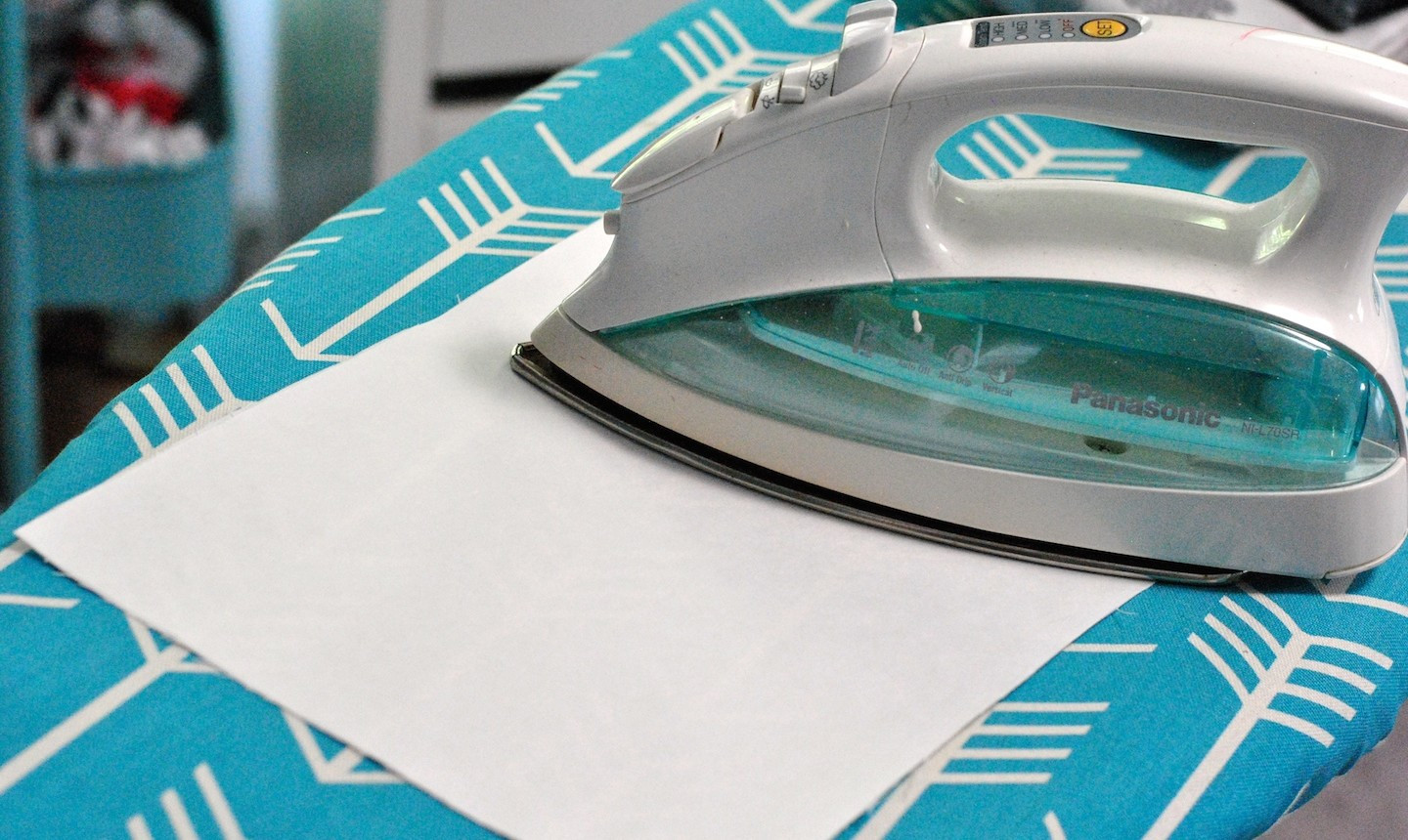 alt text: Ironing the waxy side of freezer paper to the back of fabric.