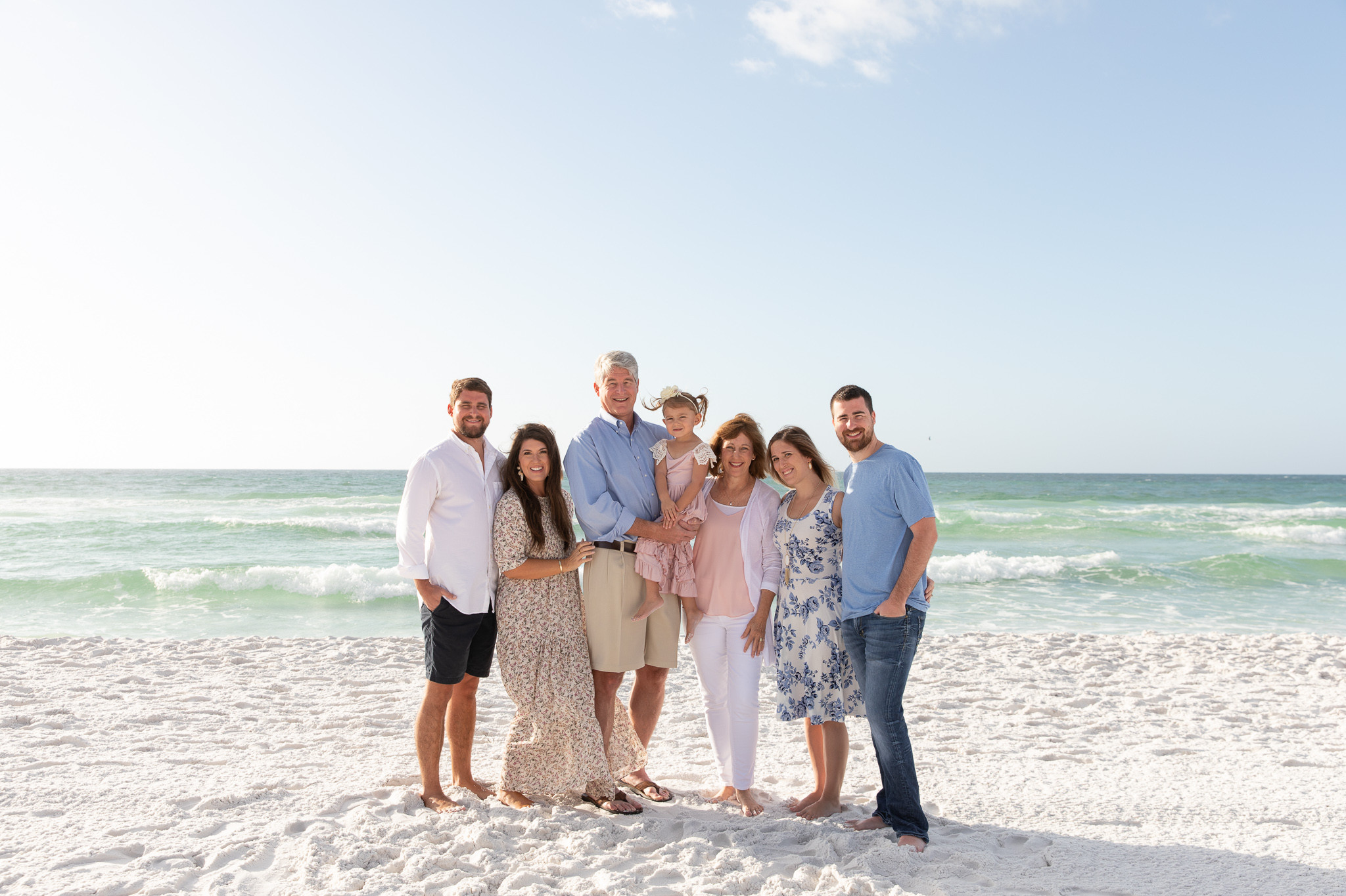 alt text: A family dressed in all white poses on the beach, creating a clean and elegant look.