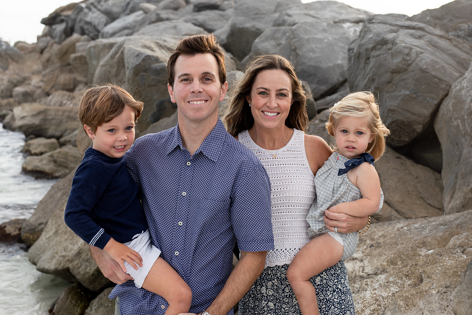 alt text: A family wearing fun, colorful outfits that reflect their personalities poses for a beach photo.