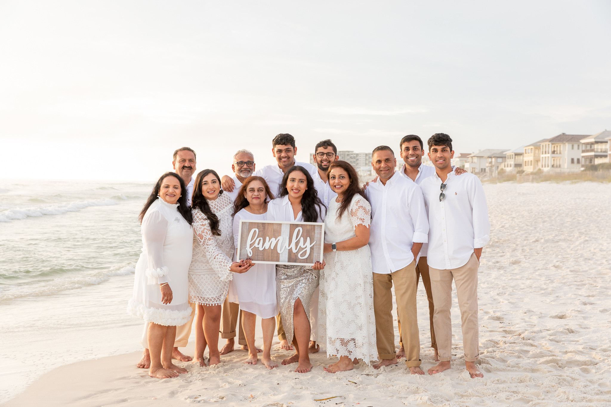 alt text: A family dressed in classic, timeless outfits poses for a photo on the beach.