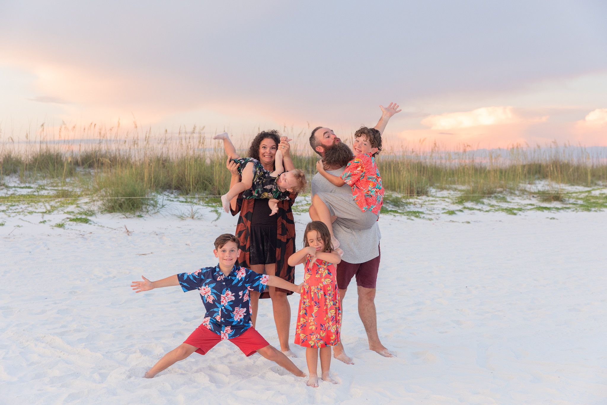 alt text: Two young sisters in matching dresses smile for a photo on the beach.