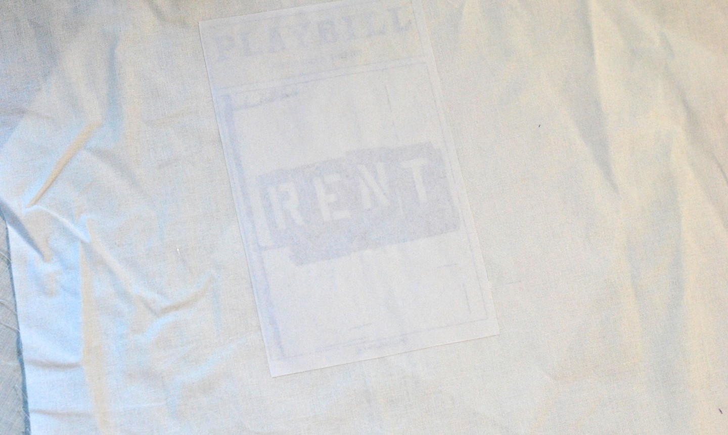 alt text: Placing a gel medium-coated image face down onto fabric and smoothing it out.