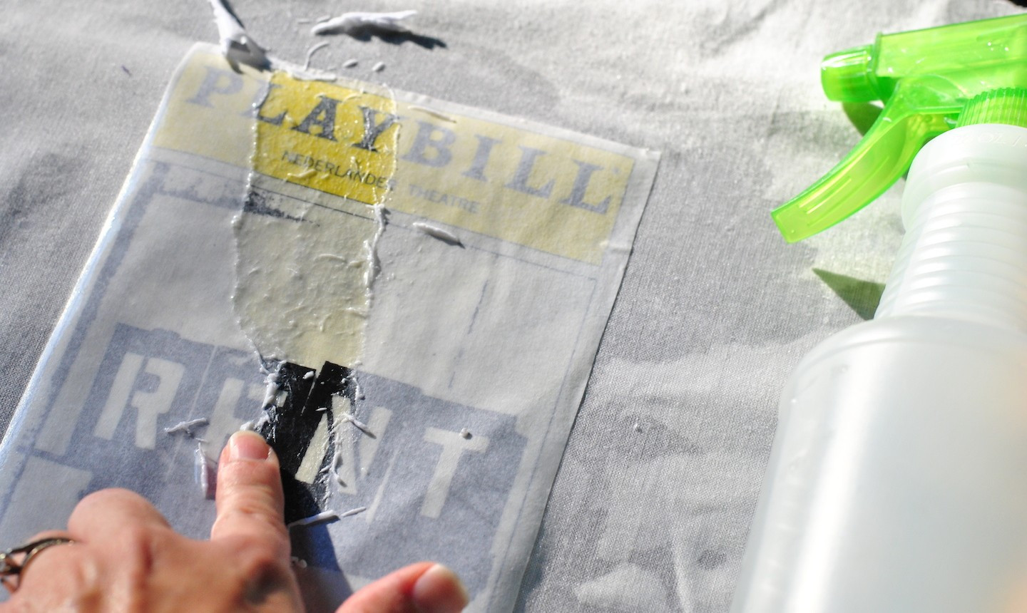 alt text: Spraying water onto a dried gel medium transfer and rubbing the paper backing.