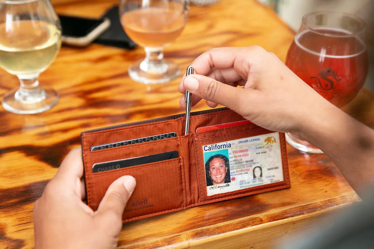 person pulling an Allett micro pen out of an Allett leather ID Wallet