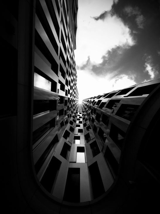 High contrast black and white photograph of a towering building emphasizing its height and scale