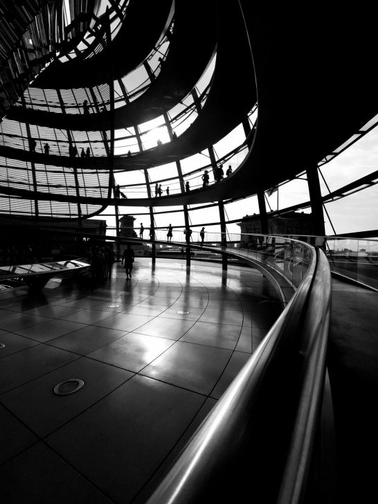 Black and white shot using a railing as a foreground element to guide the eye to figures in the distance