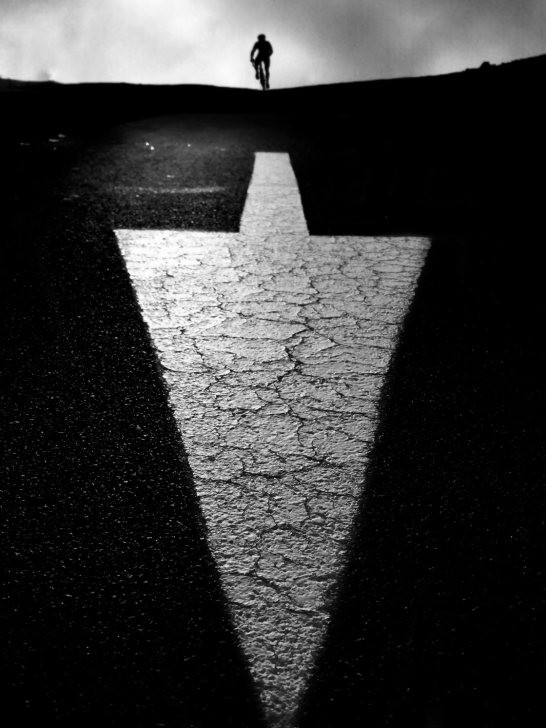 Minimalist black and white photograph of a solitary figure walking in a vast empty space