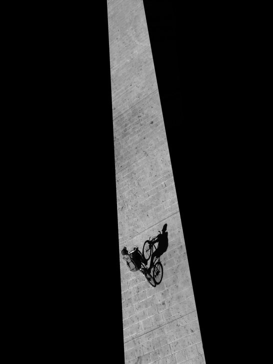 Black and white photograph of a cyclist in motion, perfectly captured using burst mode in an urban setting