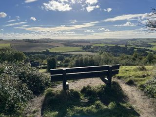 A photo of a park bench with a landscape background taken with iPhone 13 demonstrating HDR.