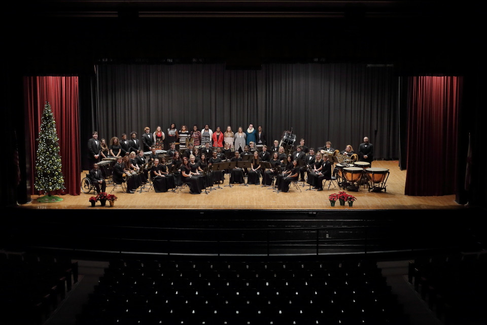 alt text: A photo of an orchestra on a stage with a conductor in the center.