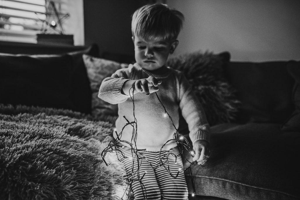 Two images showing a child interacting with Christmas lights in different poses, highlighting the versatility of using lights in DIY Christmas photos.