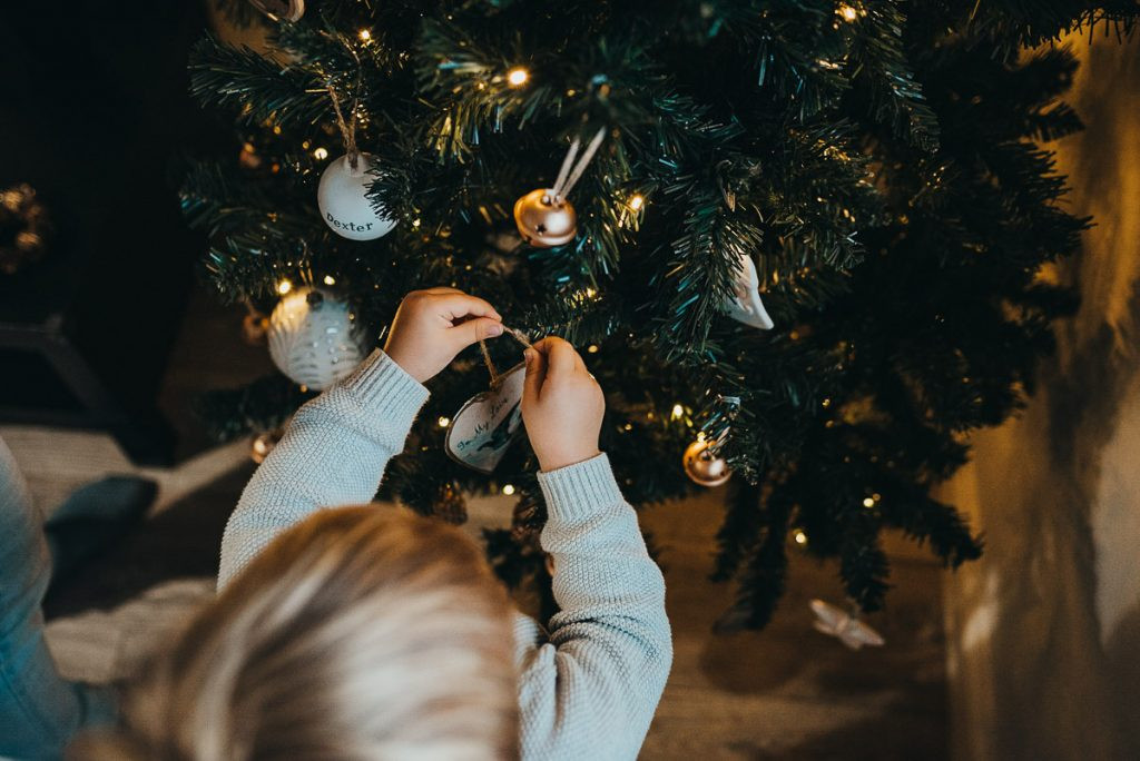 A photo taken from above, showing a child decorating a Christmas tree, illustrating creative angles for DIY Christmas photos.