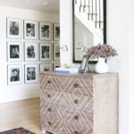 alt text: A tastefully arranged gallery wall with black and white family photos in a hallway.