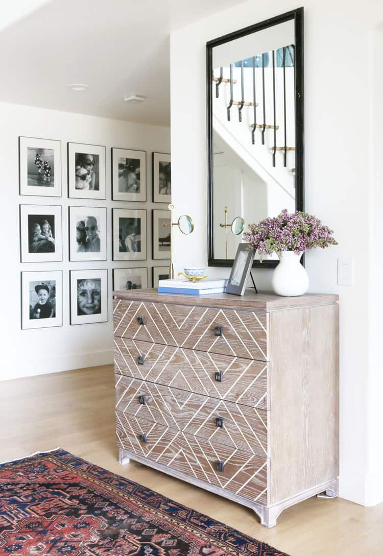 alt text: A tastefully arranged gallery wall with black and white family photos in a hallway.