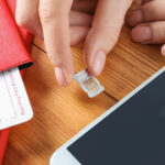 A traveler is trying to switch a SIM card on smartphone while thinking of what is stored on a SIM card