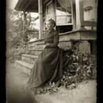 Woman wearing Victorian-era clothing. Taken on the front porch of her farmhouse.