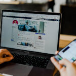 A person using a laptop to download photos from Facebook.