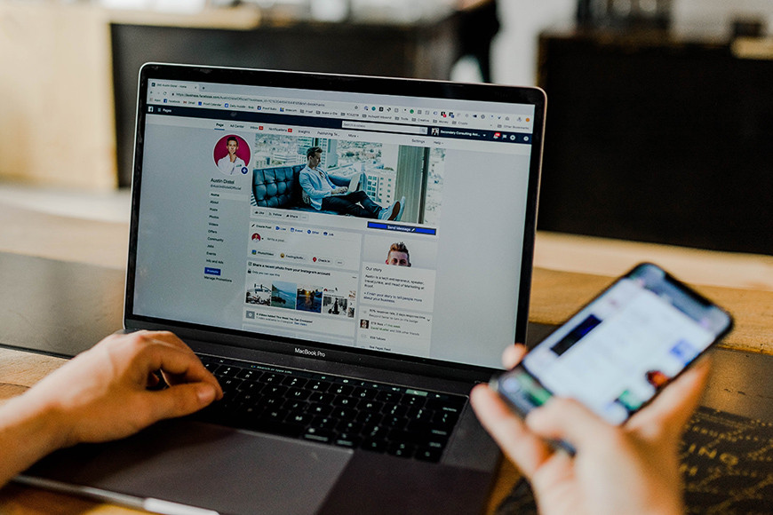 A person using a laptop to download photos from Facebook.