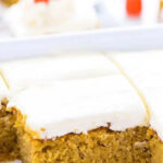 A slice of gluten-free pumpkin cake with cream cheese frosting, decorated with candy corn pumpkins.