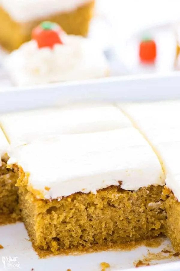 A slice of gluten-free pumpkin cake with cream cheese frosting, decorated with candy corn pumpkins.