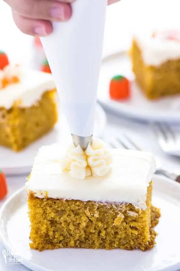 A slice of gluten-free pumpkin cake with cream cheese frosting and festive sprinkles.