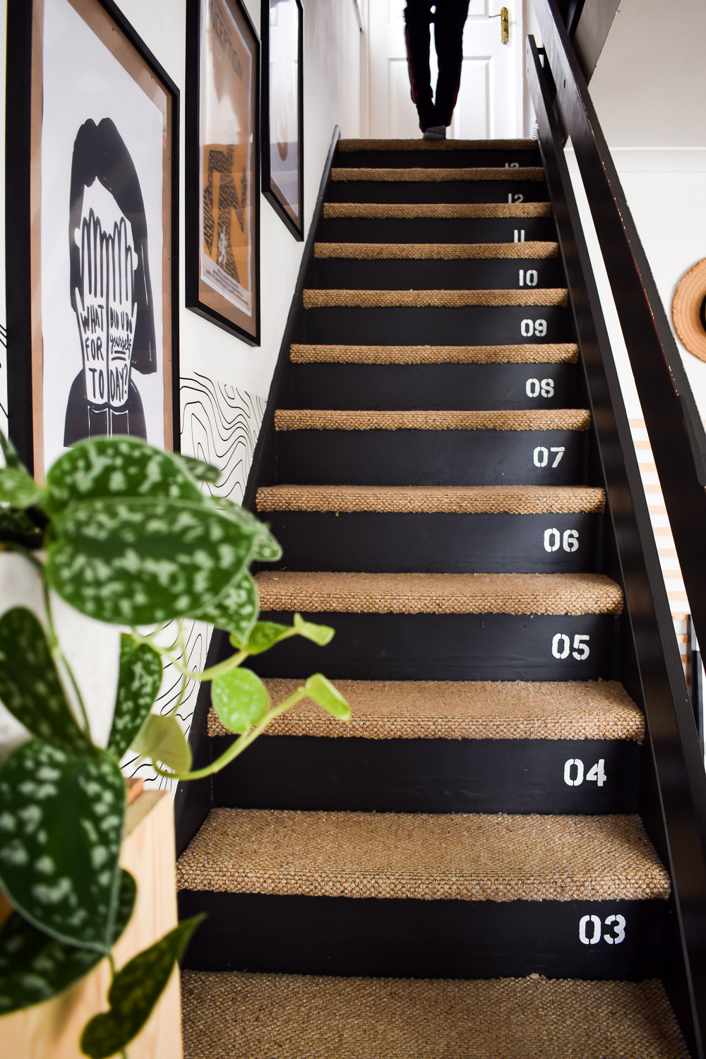 Staircase gallery wall featuring black painted stairs and carpeted treads, illustrating a classic home decor approach