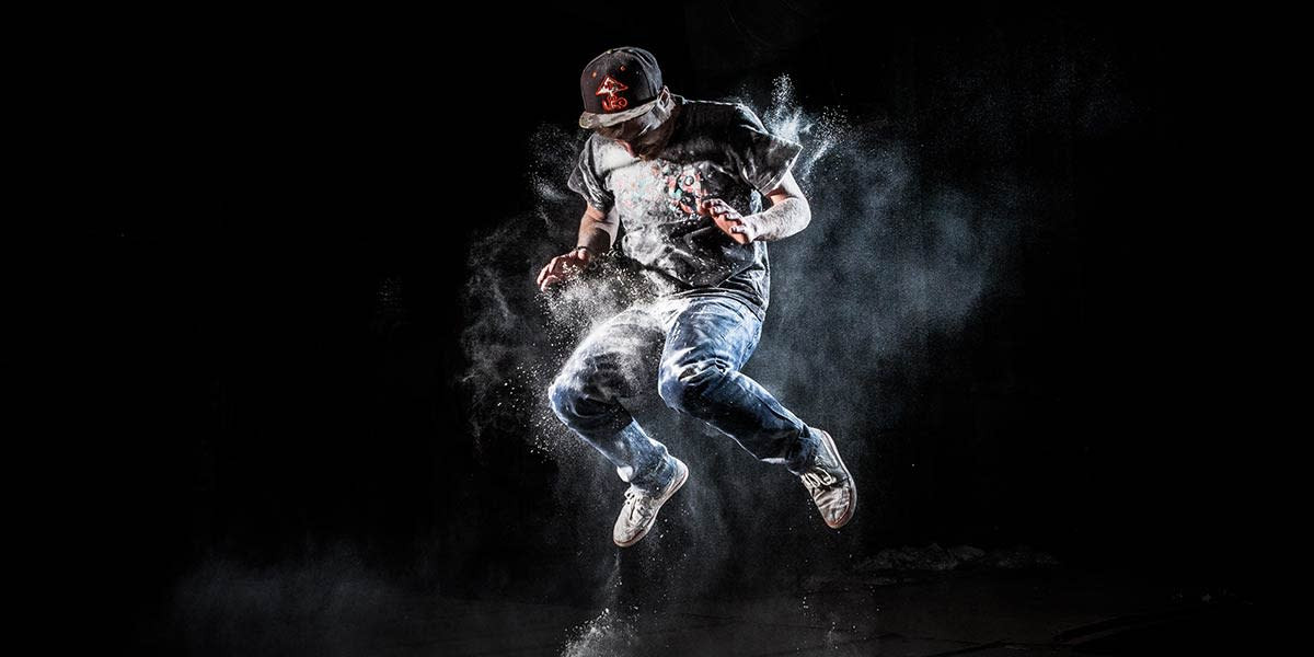 A man jumping in white powder, captured using flash photography, demonstrates creative flash techniques for dynamic images.