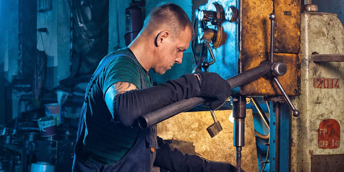 A photographer working in a machine shop using off-camera lighting, emphasizing the importance of controlled lighting in professional settings.