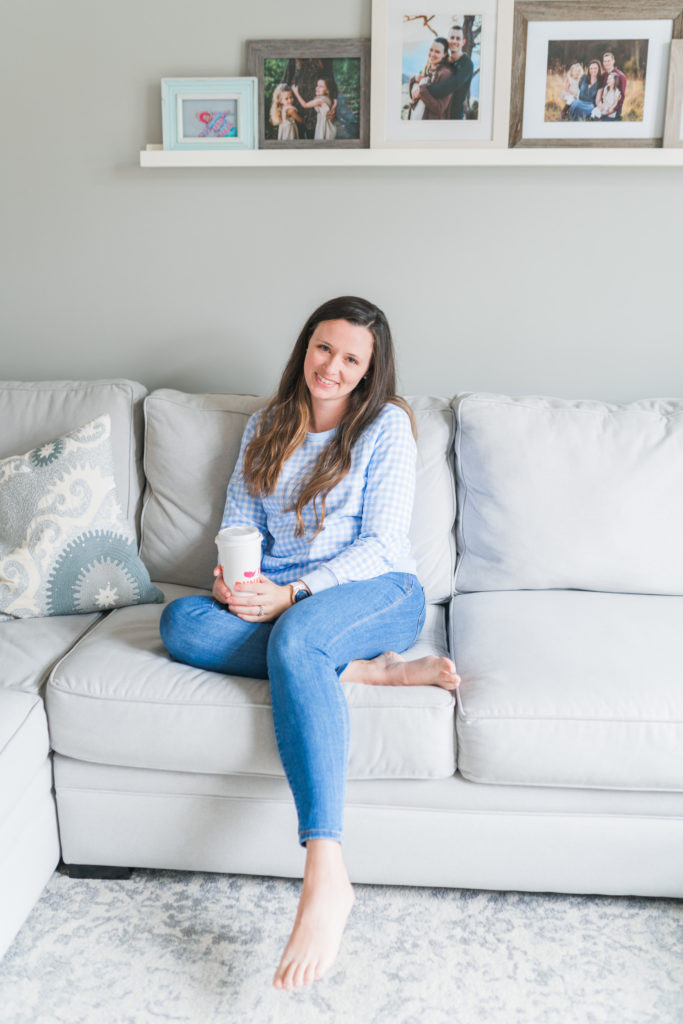 Woman on a couch with family photos on the wall