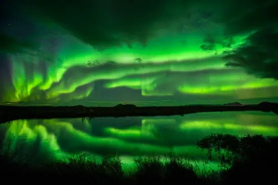 Fast-moving aurora display with vibrant green and swirling patterns, requiring shorter shutter speeds to capture detail.