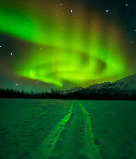 Photographer adjusting lens focus ring at night, demonstrating manual focusing technique for aurora photography.