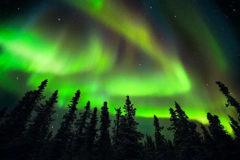 Northern lights display in Alaska, showcasing vibrant green and purple hues dancing across the night sky.