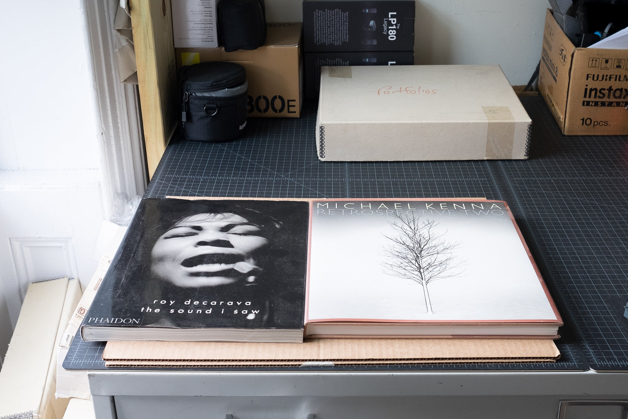 Coffee table books used to flatten a curled photo print, demonstrating a method to fix packaging-related issues.