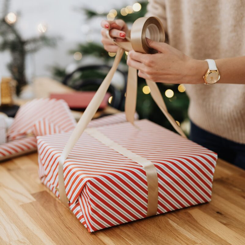 Person folding the ends of wrapping paper on a picture frame.