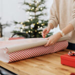 Woman wrapping a picture frame with brown paper.