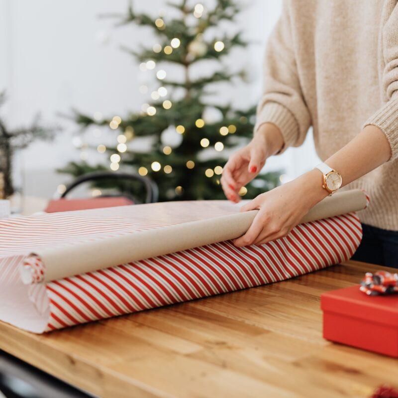 Woman wrapping a picture frame with brown paper.