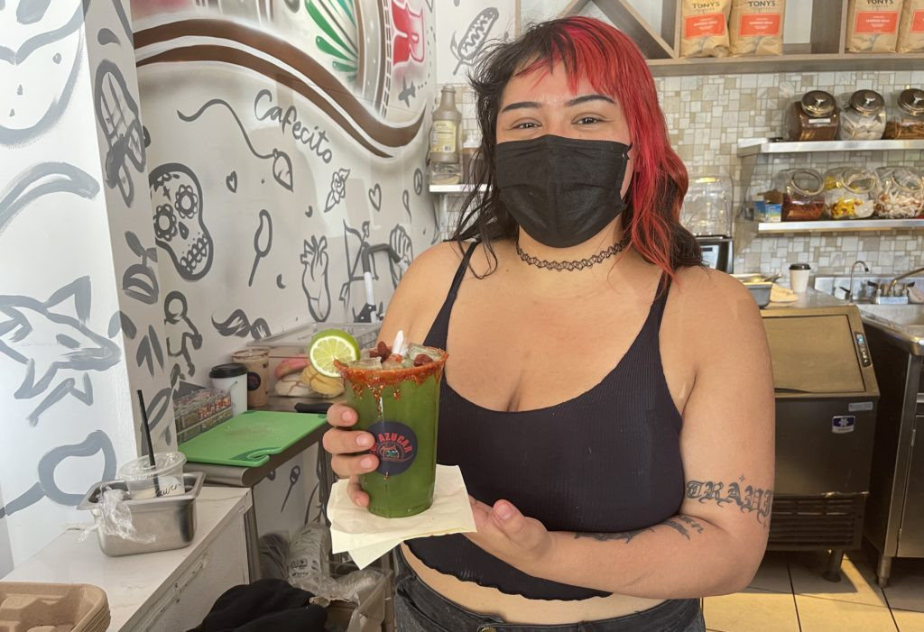 Con Azucar Café Manager Anais Salazar showcasing a pepino con limon drink