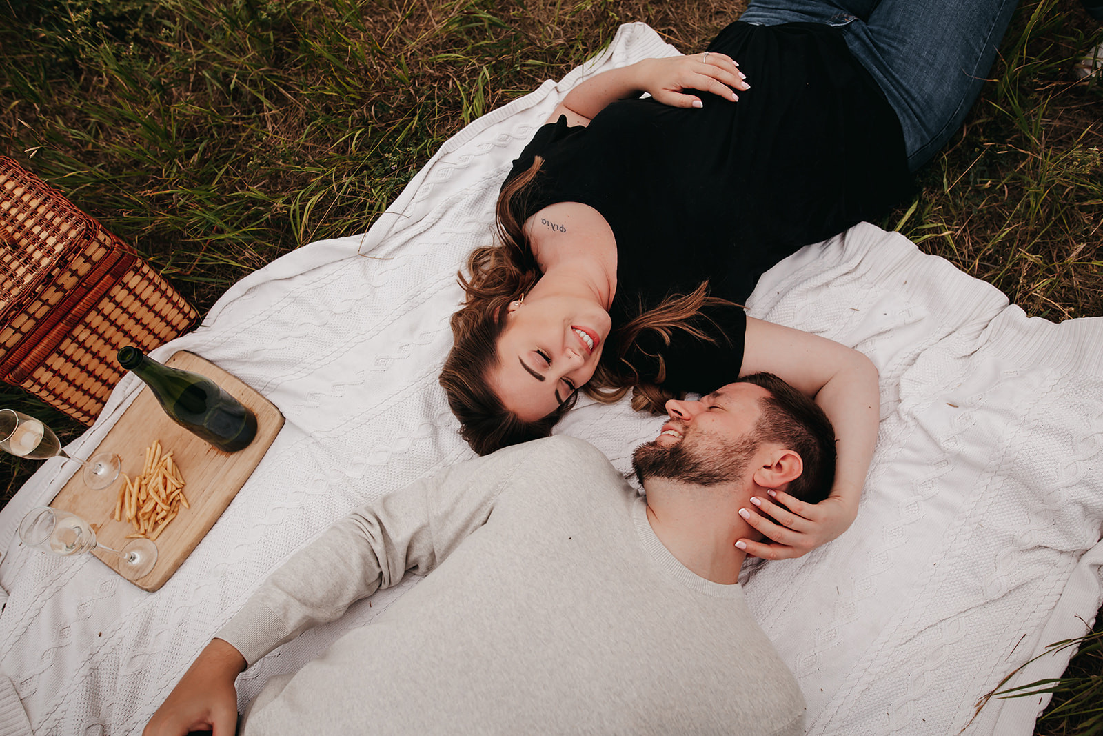 Couple laying in a field, demonstrating relaxed and practiced engagement poses