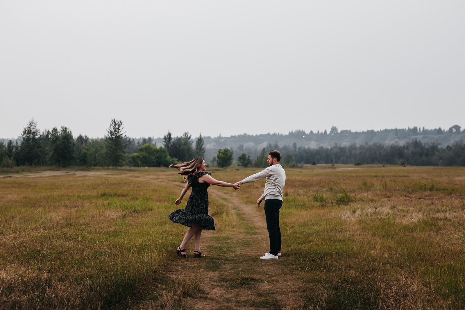 Couple in a field, showcasing natural and comfortable poses for engagement photos