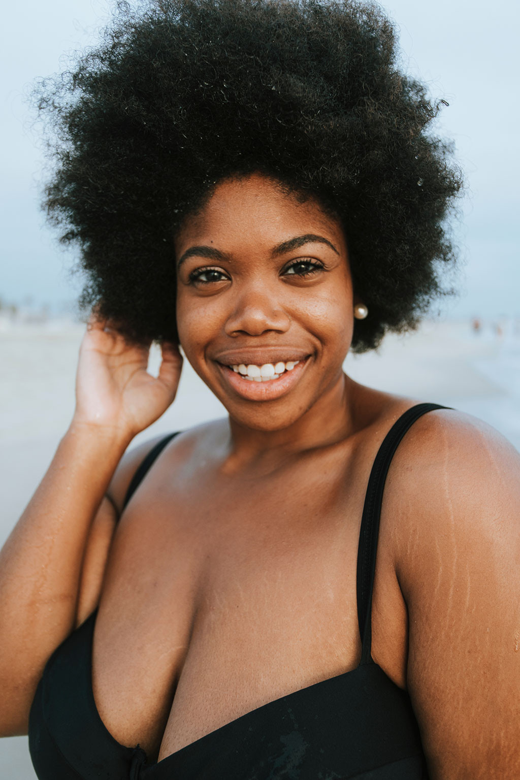 Confident plus-size African American woman posing on the beach, promoting diversity in stock images