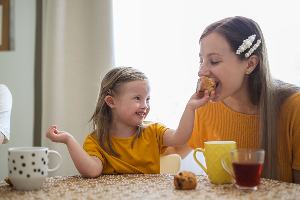 Child feeding her mother a cookie, depicting everyday moments with disabilities in stock photos
