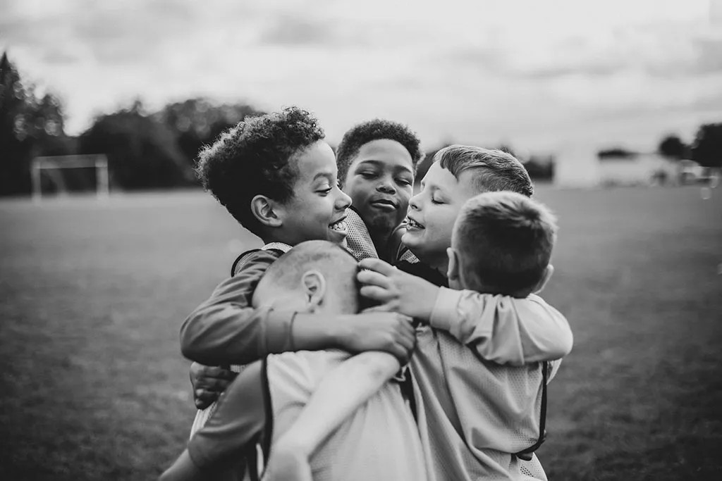 Black and white photo of kids playing soccer, capturing candid family moments in stock photography