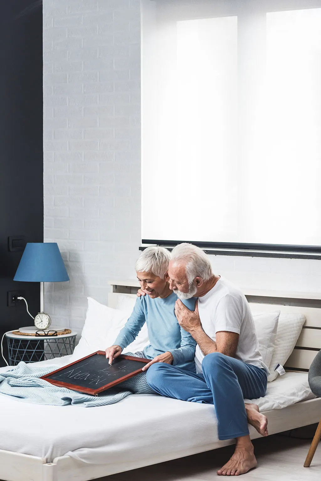 Senior couple in bed laughing, representing older age groups in stock photography
