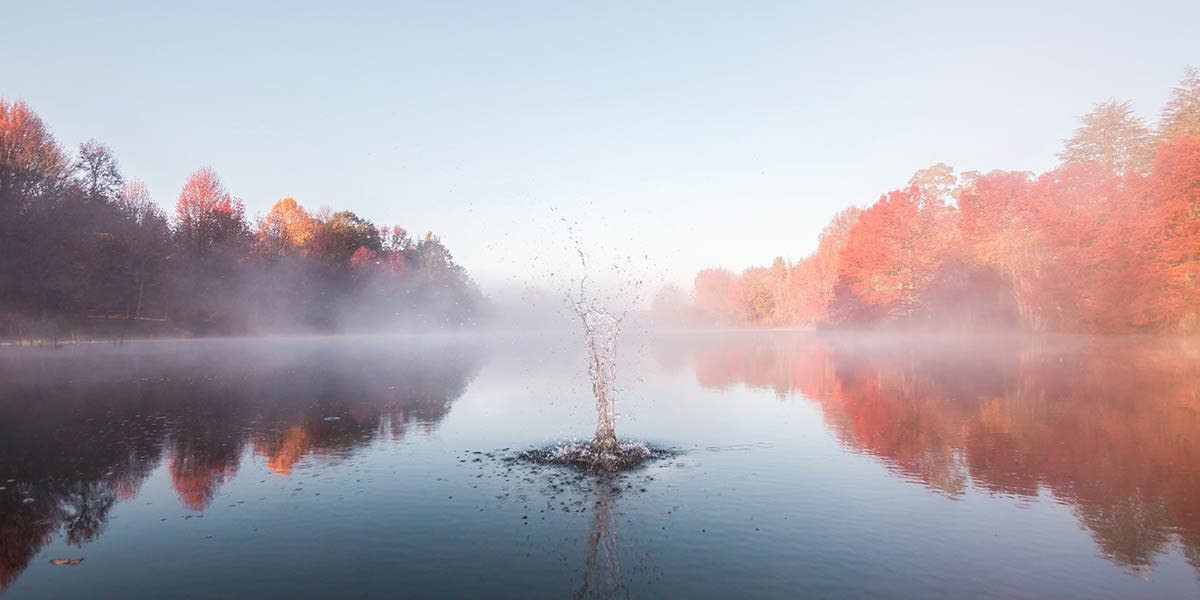 Rocks splashing into a foggy lake, showcasing depth through foreground, middle ground, and background elements in landscape photography.