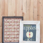 Two finished DIY rustic picture frames displaying fall apple designs, enhancing the seasonal decor on a mantelpiece.