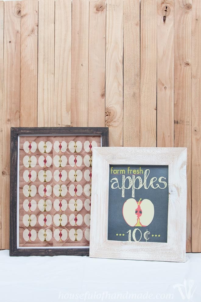 Two finished DIY rustic picture frames displaying fall apple designs, enhancing the seasonal decor on a mantelpiece.