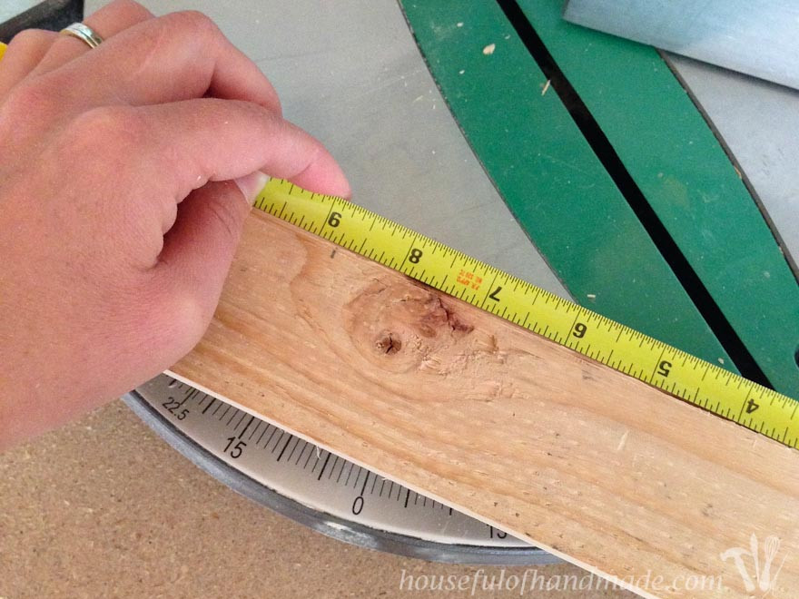 Rustic wood being measured with a tape measure, preparing for cuts in the DIY picture frame construction process.