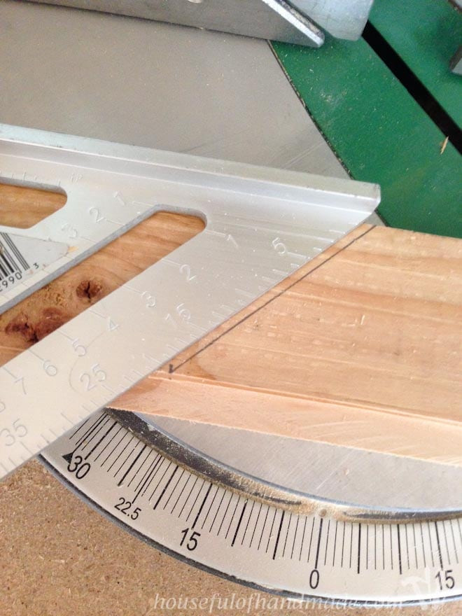 A rafter square positioned on rustic wood, used for marking angles in the construction of wooden picture frames.