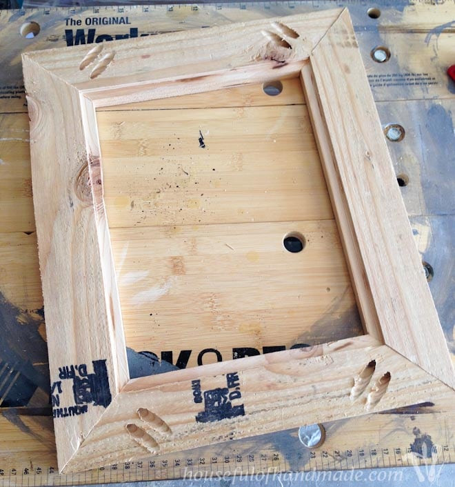 DIY wood frame with wood glue applied in the corners, resting on a workbench during the assembly process.