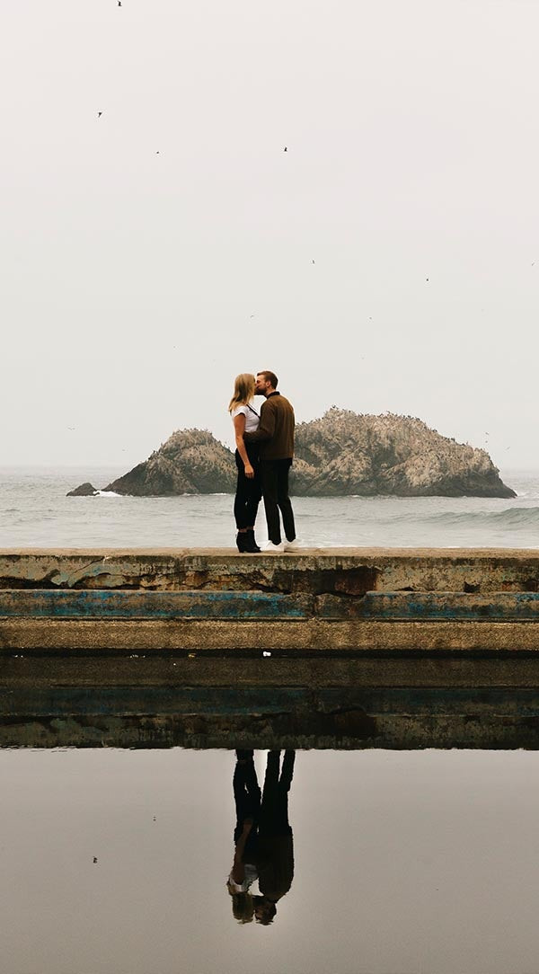Professionally edited photo of a couple kissing on a dock with refined shadows